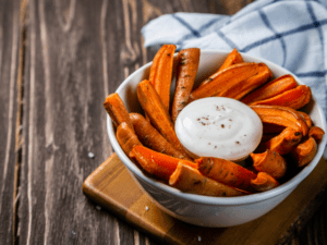 A bowl of roasted carrots with a creamy dipping sauce.