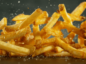 French fries being seasoned as they fly in midair.