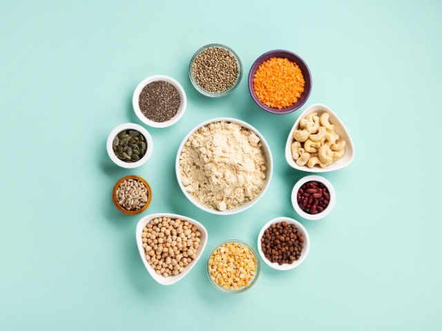A collection of various seeds, legumes, and nuts arranged in a circular pattern, showcasing ingredients like chia seeds, cashews, chickpeas, and lentils.