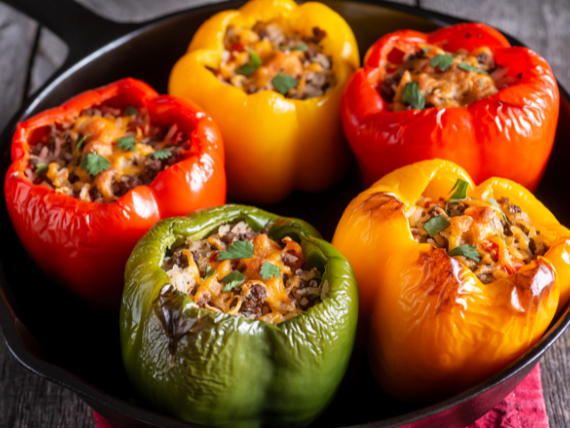 Colorful bell peppers stuffed with rice and meat, baked in a cast iron skillet.