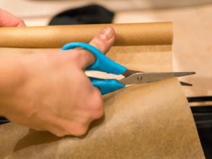 A pair of scissors cutting parchment paper.