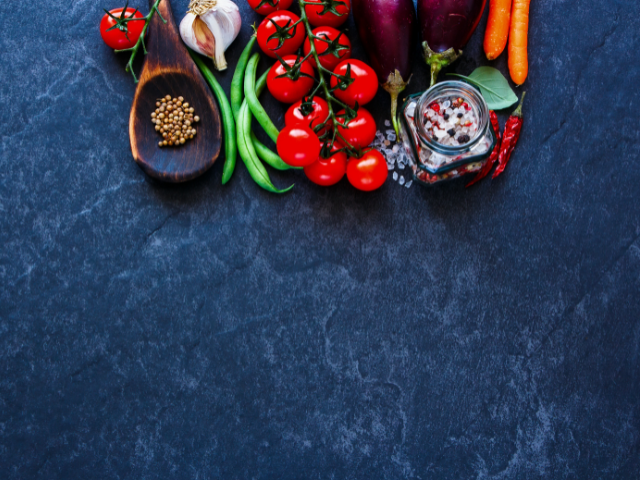 Fresh vegetables arranged on a dark slate background.