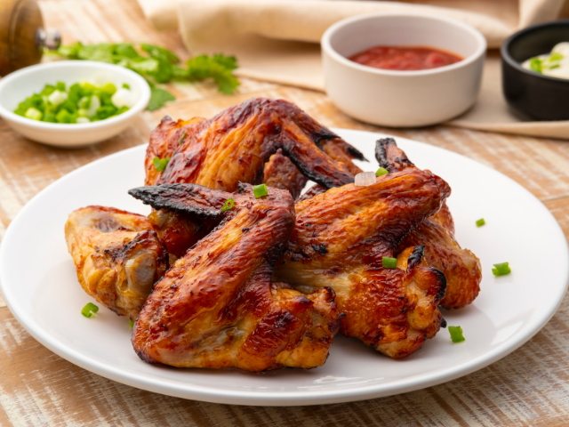 Grilled chicken wings served on a plate with dipping sauces.