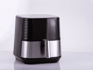 A white air fryer with a removable basket, placed on a kitchen counter.