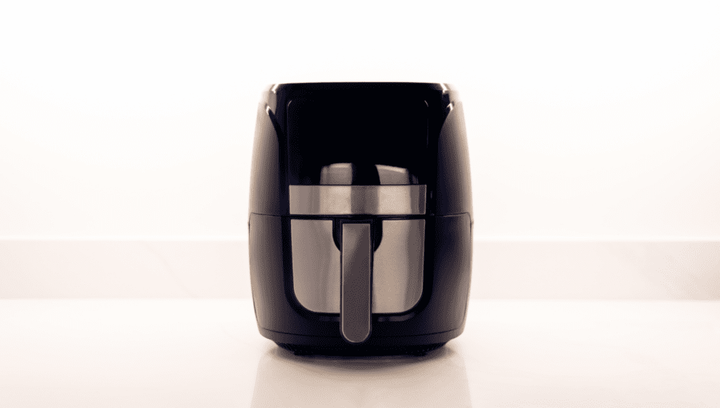 A black air fryer sitting on a clean kitchen countertop.