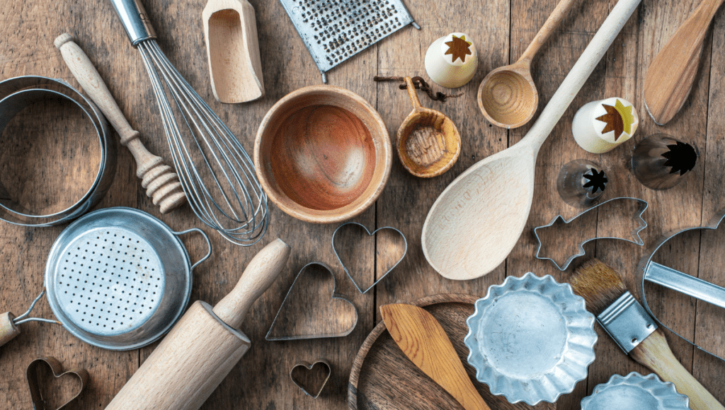 Various wooden and metal kitchen utensils spread out on a wooden surface.