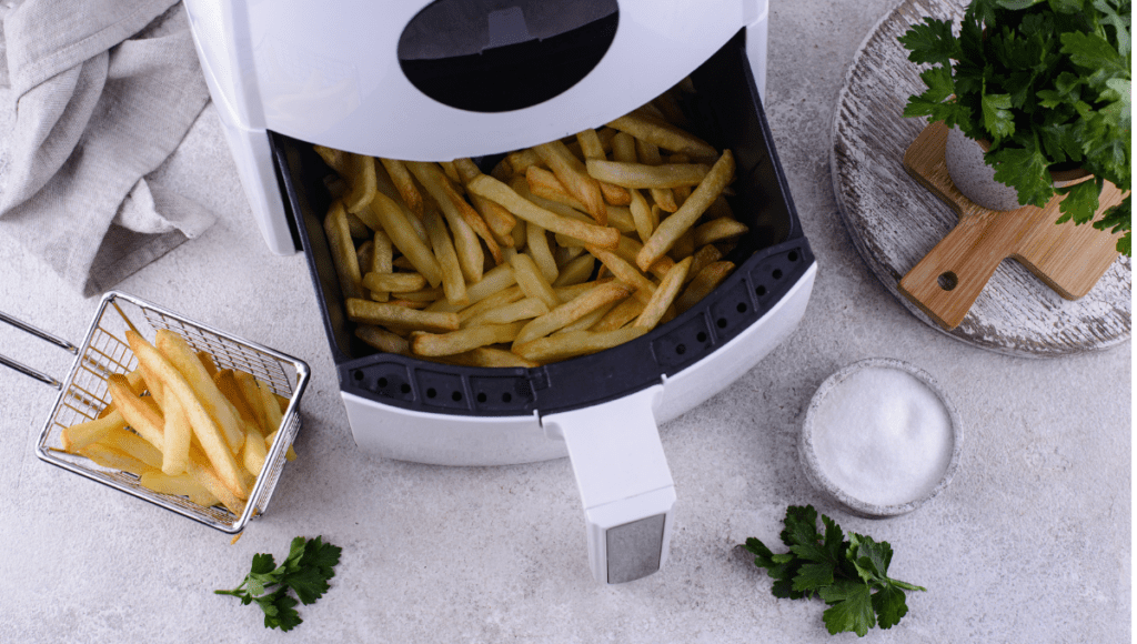 Freshly cooked French fries in an air fryer with a side basket.