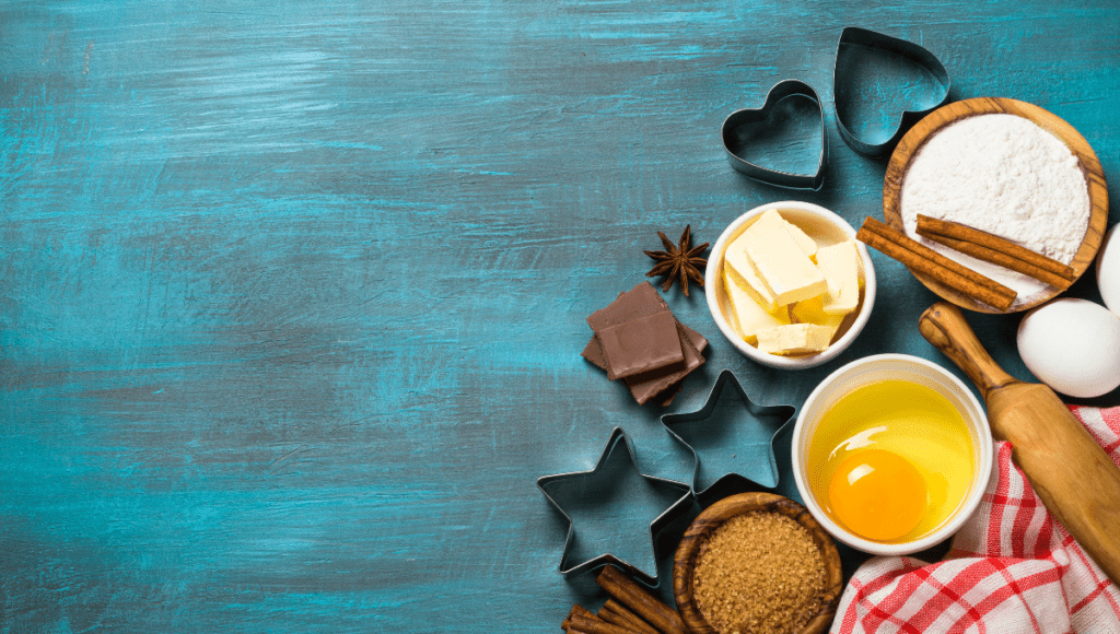Ingredients and cookie cutters arranged on a textured teal background.