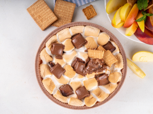 A s'mores dessert with toasted marshmallows, chocolate pieces, and crackers.