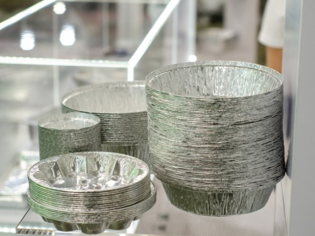 Stacks of shiny aluminum foil pans in various sizes, displayed at a store.