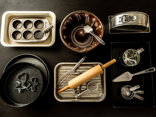 A variety of baking tools and molds laid out on a black background.