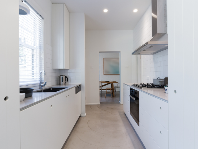 A modern minimalist kitchen with white cabinetry and sleek design.