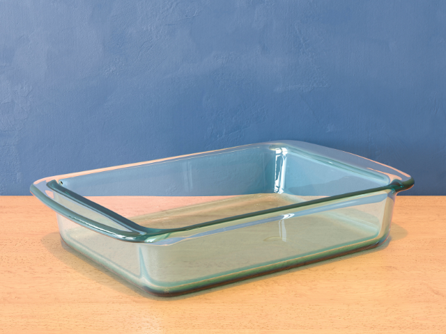 Empty glass baking tray on a wooden surface with a blue background.