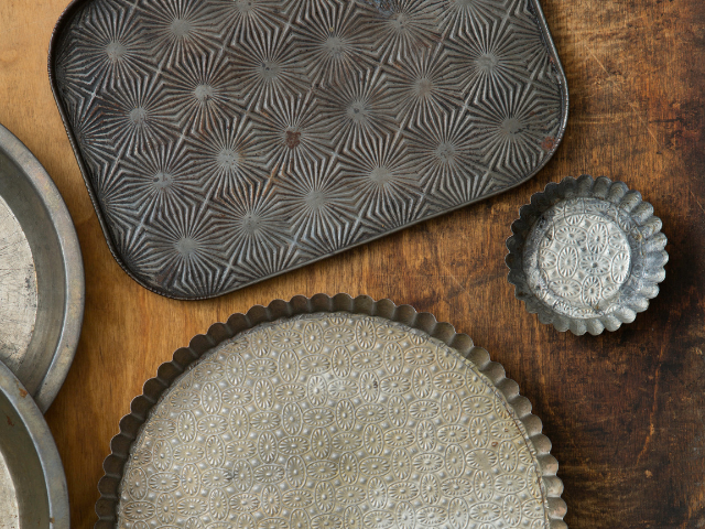 Vintage baking trays with intricate designs displayed on a rustic wooden surface.