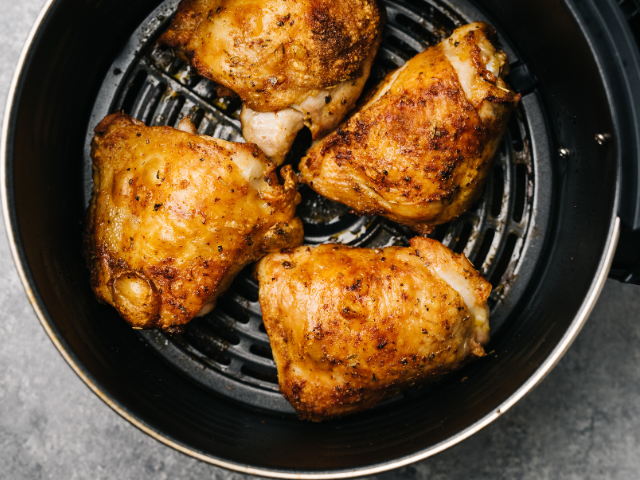 Golden-brown chicken thighs cooked to perfection inside an air fryer basket.