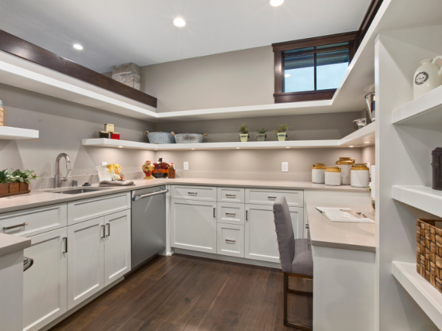 A spacious, well-organized kitchen pantry with white cabinetry, open shelves, and various jars and kitchen supplies neatly arranged